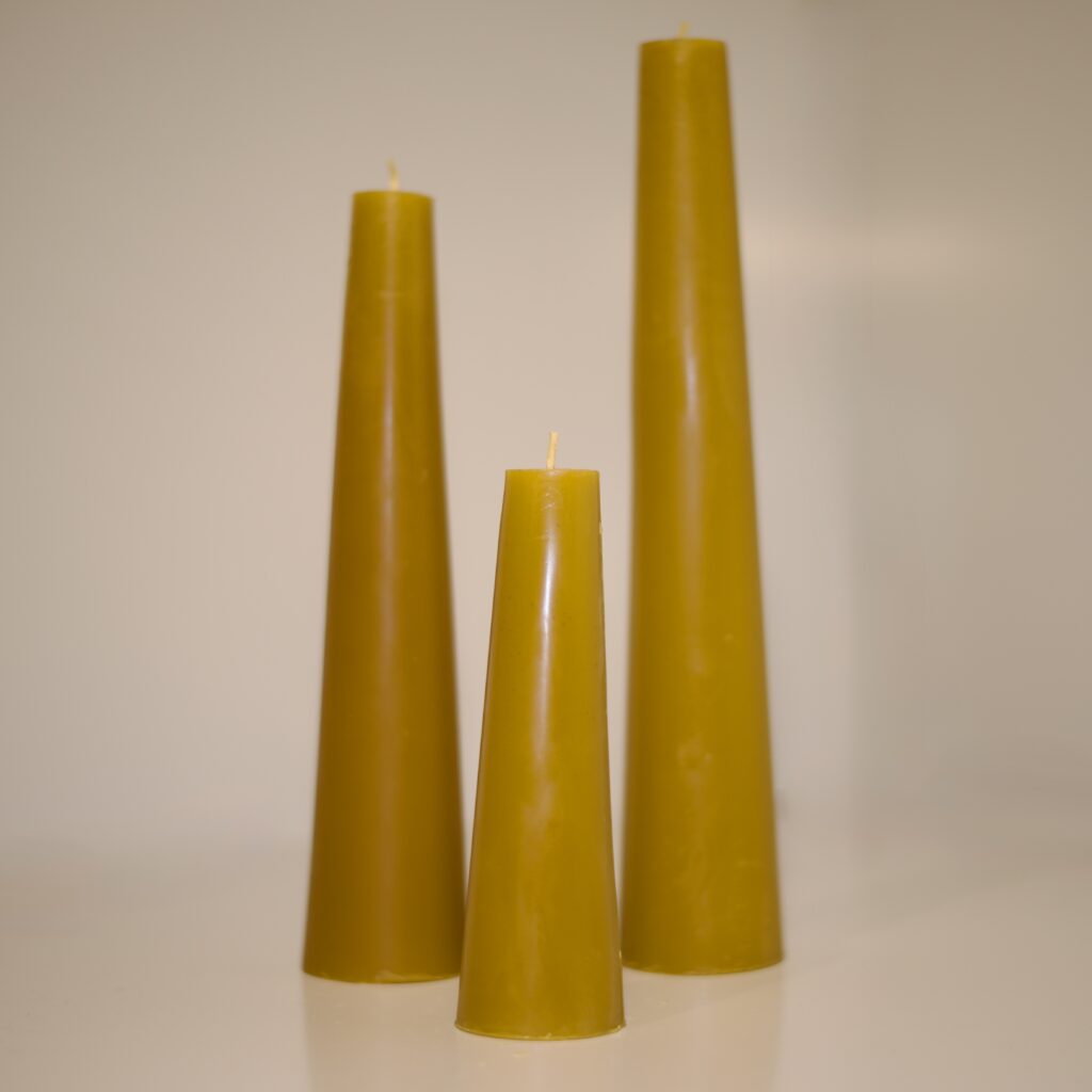 Three tapered beeswax pillar candles in graduated heights